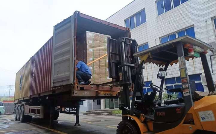 Forklift loading palletized cartons of custom rubber parts into shipping container