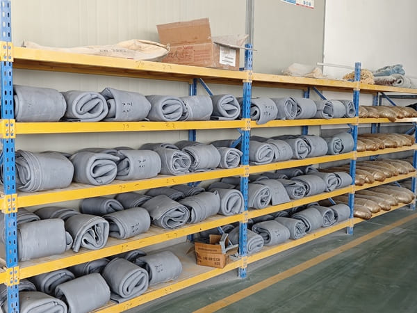 Shelves in a warehouse storing neatly rolled rubber materials, categorized and arranged for efficient storage.