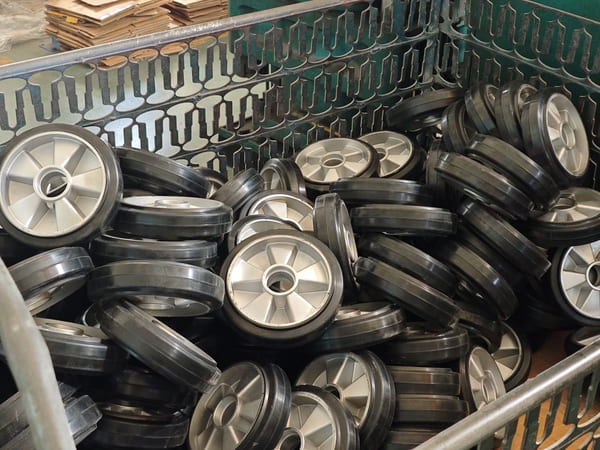 A metal storage bin filled with black and silver rubber wheels, ready for assembly or shipment.