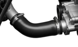 Close-up of a rubber lower radiator hose with metal clamps attached to an engine, showcasing the hose's curved shape and secure fitment to the engine components