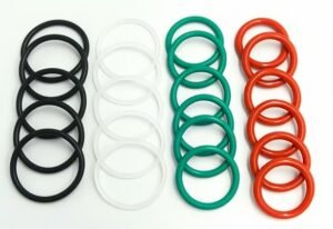 O-ring selection, black, white, green, and red rubber O-rings, assorted sizes, arranged in four color groups, industrial sealing application.