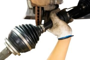 Mechanic installing a CV joint with boot into a vehicle’s suspension system, ensuring proper alignment and sealing.