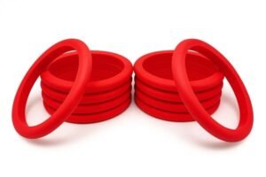 Multiple red D-ring seals stacked in two piles with additional rings leaning on top, designed for pneumatic and hydraulic sealing.