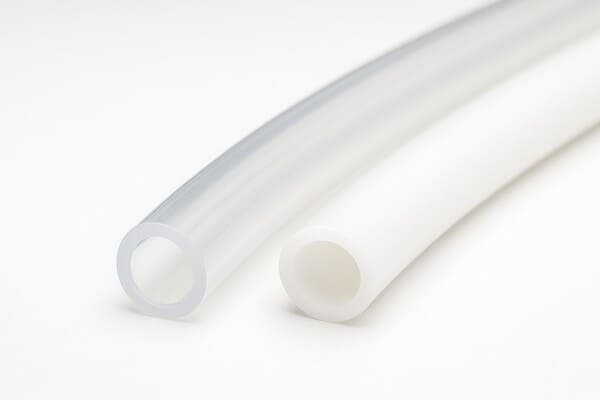 Silicone tubing comparison, transparent fumed silicone tube with high clarity and strength placed next to opaque white common silicone tube, both on clean white background.