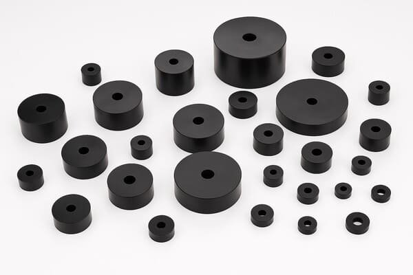 Assorted rubber bumpers in cylindrical shapes with center holes, durable shock-absorbing mounts for vibration damping and industrial machinery protection.