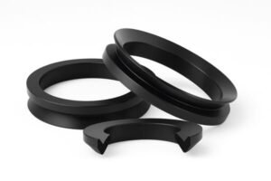 Black rubber V-ring seals, close-up on white background, showing conical lip design, flexible sealing edge, and protective dust barrier for rotating shafts.