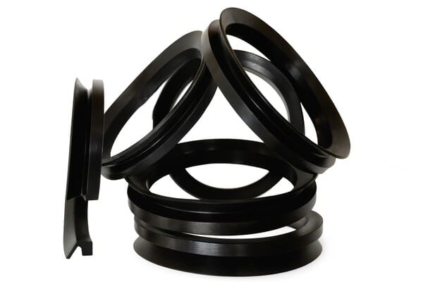 Black rubber V-ring seals in various sizes, stacked and leaning together on a white background, showing flexible conical lip design for shaft sealing and dust protection.
