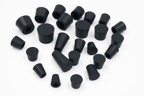 Black rubber stoppers in mixed sizes, conical plugs for laboratory glassware sealing, machinery protection, and leak prevention.