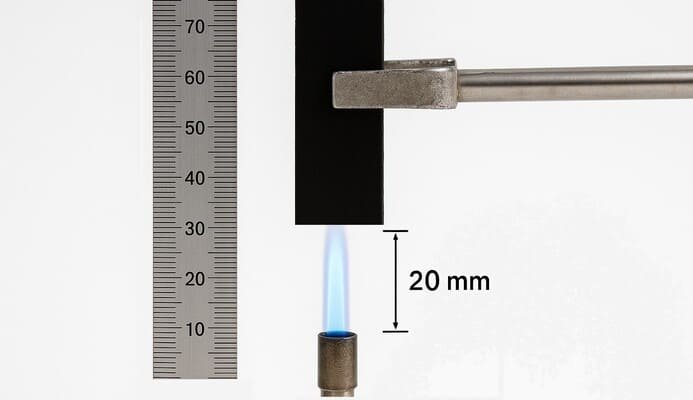 UL94 V-0 test setup showing 20 mm blue flame applied to vertical rubber specimen, precise distance measurement with metal ruler for flammability evaluation.