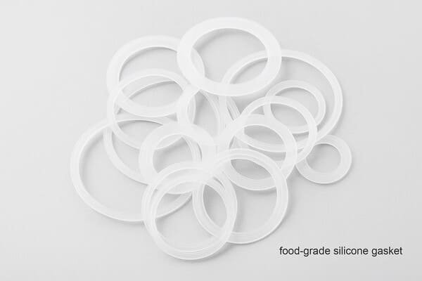 Food-grade silicone gasket, translucent white rings, clean white background, stacked and overlapping for bottle cap sanitary sealing.