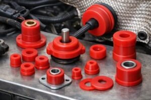Silicone bushings assortment displayed on engine bay panel, red sleeves with metal inserts and washers, for mount isolation.