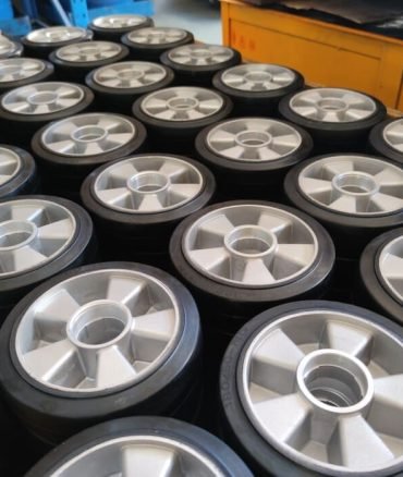 Pallet truck rubber wheels 170mm, silver aluminum hubs with black tread, stacked in production batch for material handling equipment.
