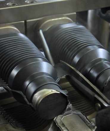 Rubber bellows manufacturing process, close-up of molded flexible seals with corrugated structure for dust protection and vibration isolation.